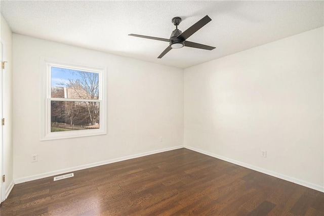 empty room with visible vents, dark wood-type flooring, baseboards, ceiling fan, and a textured ceiling