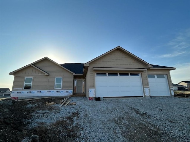 view of front of house with gravel driveway, board and batten siding, and a garage