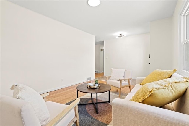 living room featuring visible vents, baseboards, and wood finished floors