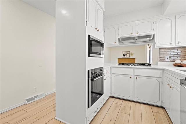 kitchen featuring visible vents, light wood-style flooring, white cabinets, and stainless steel appliances