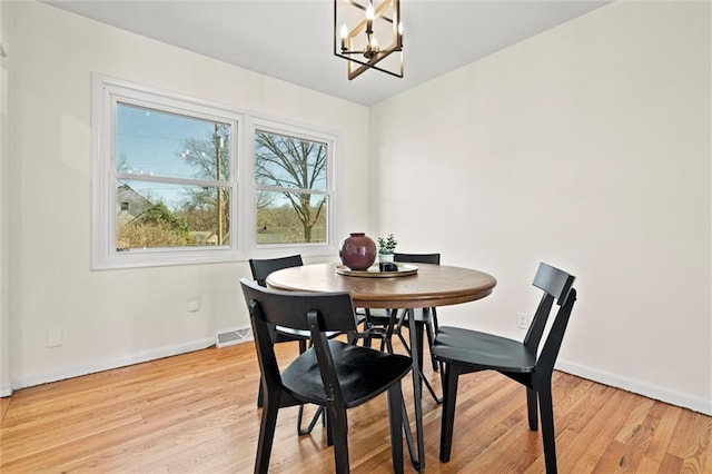 dining room with a notable chandelier, visible vents, light wood-style flooring, and baseboards