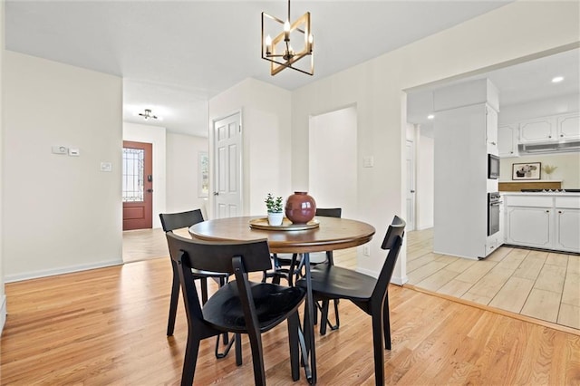 dining room with light wood-type flooring, baseboards, and an inviting chandelier