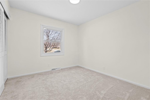 spare room with carpet flooring, baseboards, and visible vents