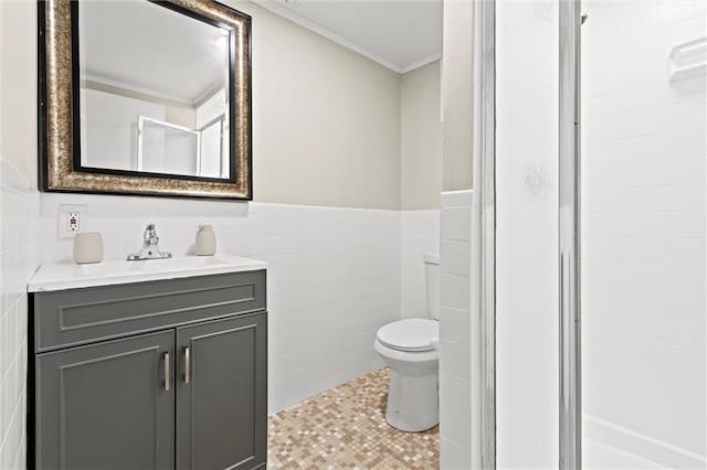 bathroom with vanity, a wainscoted wall, a stall shower, tile walls, and toilet