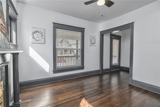 empty room featuring a ceiling fan, dark wood-style floors, and baseboards