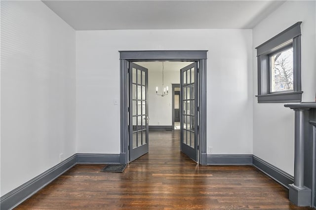 spare room with visible vents, wood finished floors, french doors, baseboards, and a chandelier