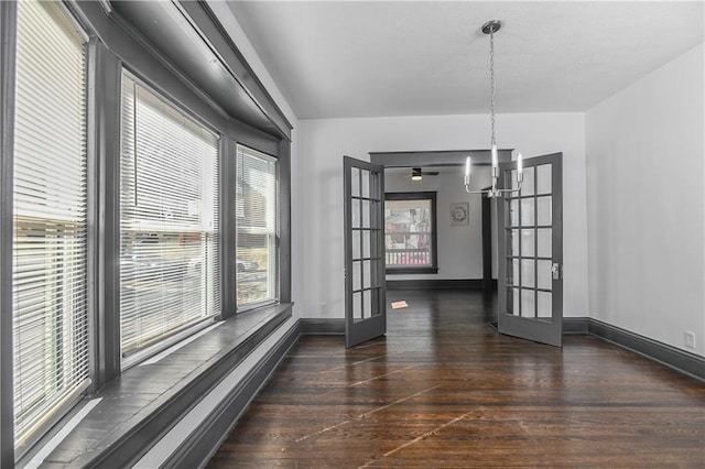 unfurnished dining area featuring an inviting chandelier, wood finished floors, french doors, and baseboards