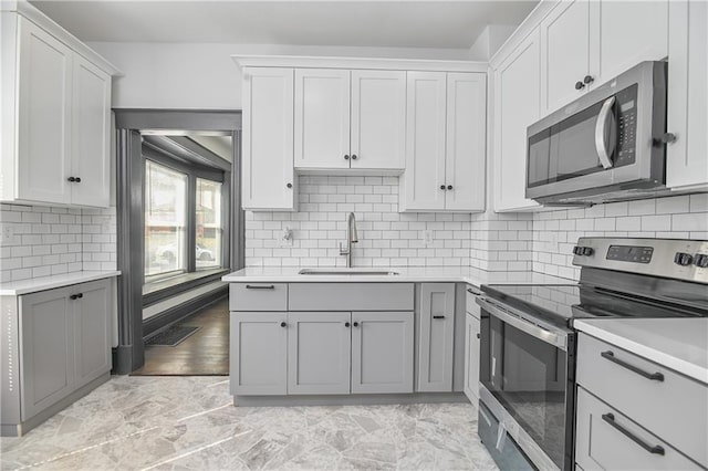 kitchen featuring light countertops, gray cabinets, appliances with stainless steel finishes, and a sink