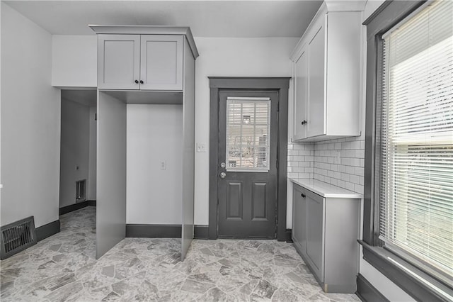 interior space featuring decorative backsplash, light countertops, visible vents, and gray cabinetry