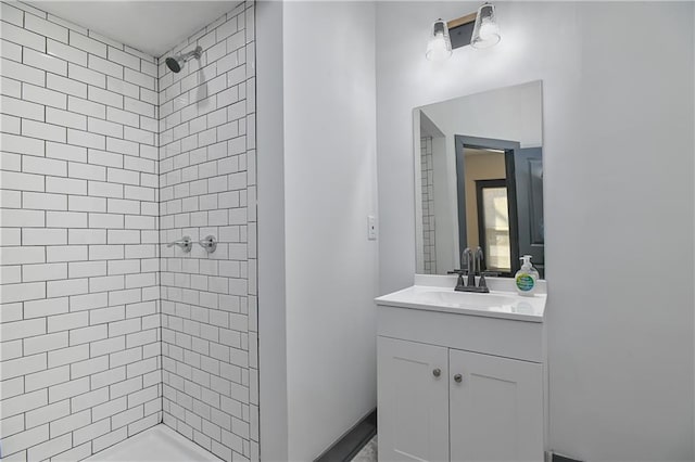 bathroom featuring tiled shower and vanity