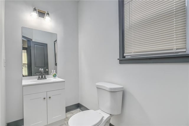 half bath with toilet, vanity, and baseboards