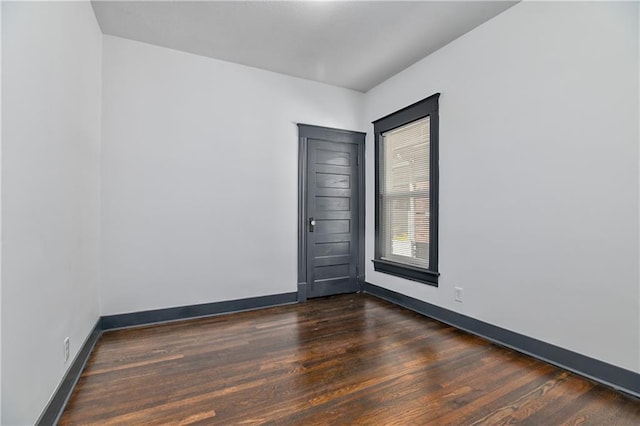 empty room featuring dark wood-style floors and baseboards