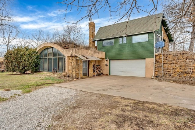 view of front facade with concrete driveway, a garage, and a chimney