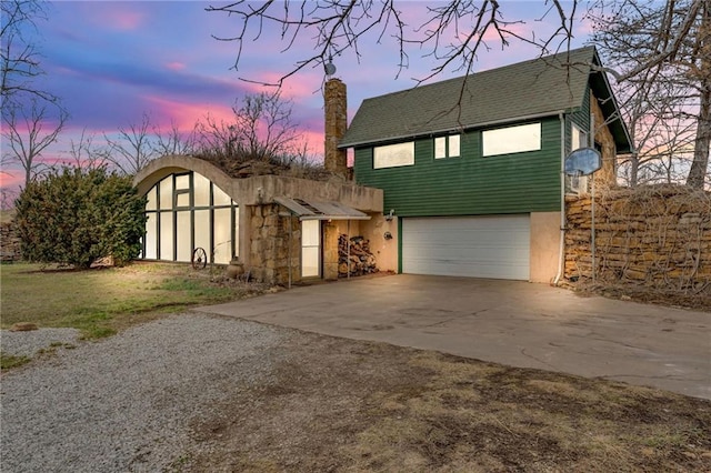 view of front of home featuring a chimney, stucco siding, an attached garage, and concrete driveway