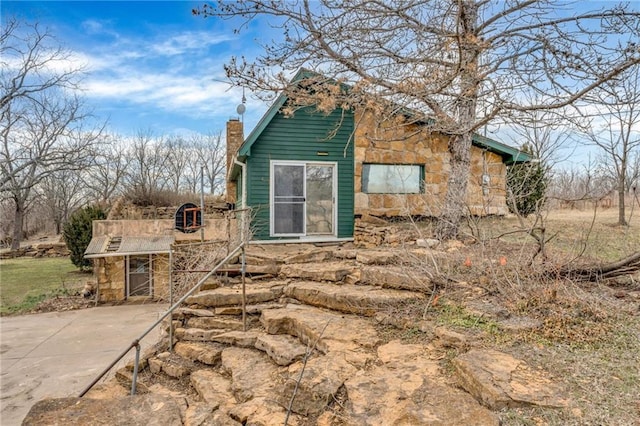 view of home's exterior featuring stone siding and a chimney