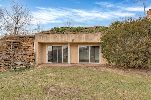 back of house with a yard and stucco siding