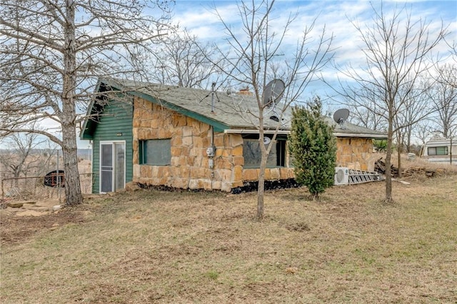 exterior space featuring stone siding and a lawn