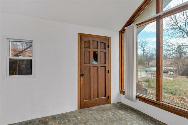 foyer featuring lofted ceiling, brick floor, and a wealth of natural light