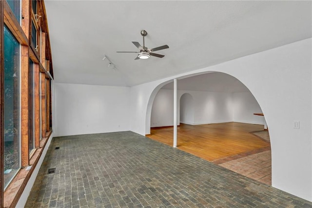 unfurnished room featuring track lighting, arched walkways, visible vents, and ceiling fan