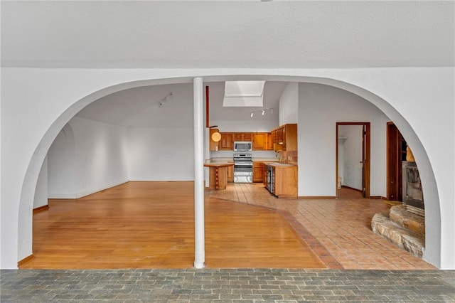 interior space with a sink, baseboards, a textured ceiling, and light wood-style flooring