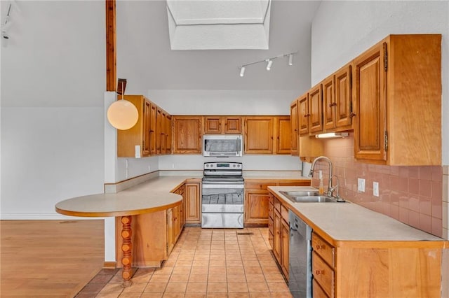 kitchen featuring a peninsula, stainless steel appliances, light countertops, and a sink