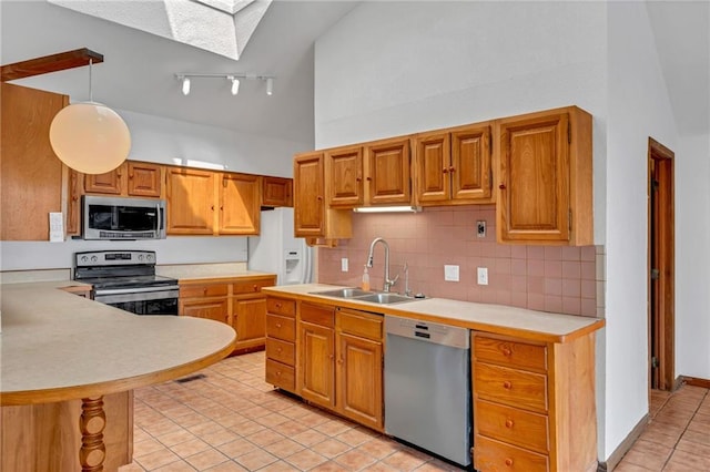 kitchen featuring high vaulted ceiling, a sink, appliances with stainless steel finishes, light countertops, and light tile patterned floors