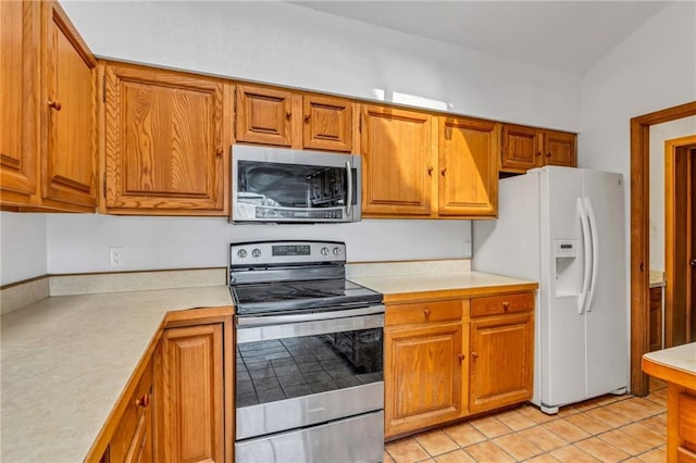 kitchen featuring brown cabinetry, light tile patterned floors, appliances with stainless steel finishes, and light countertops