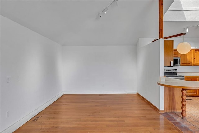 interior space featuring baseboards, light countertops, a kitchen bar, appliances with stainless steel finishes, and light wood-style floors