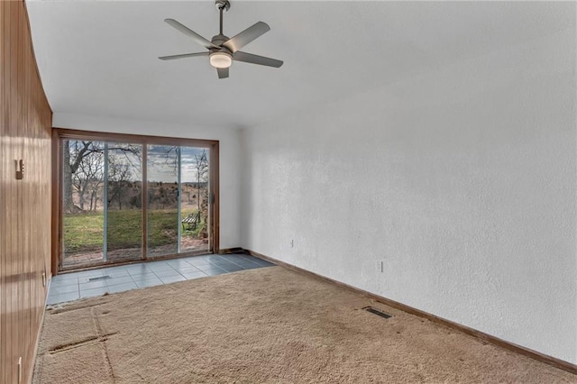 carpeted empty room with visible vents, baseboards, ceiling fan, and a textured wall