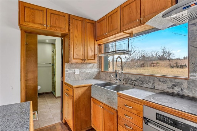 kitchen featuring electric stovetop, brown cabinets, oven, and a sink