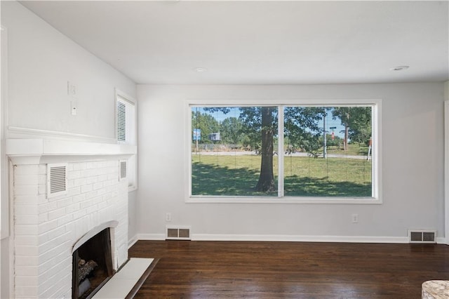 unfurnished living room featuring a brick fireplace, a healthy amount of sunlight, and visible vents