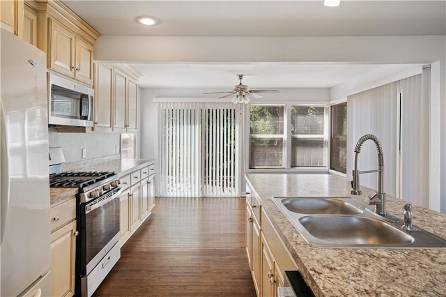 kitchen with a sink, dark wood finished floors, appliances with stainless steel finishes, light countertops, and ceiling fan