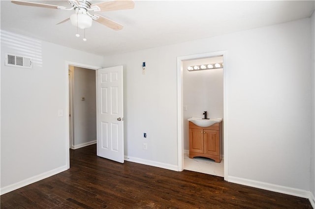 unfurnished bedroom featuring visible vents, ensuite bathroom, a sink, dark wood-style floors, and baseboards