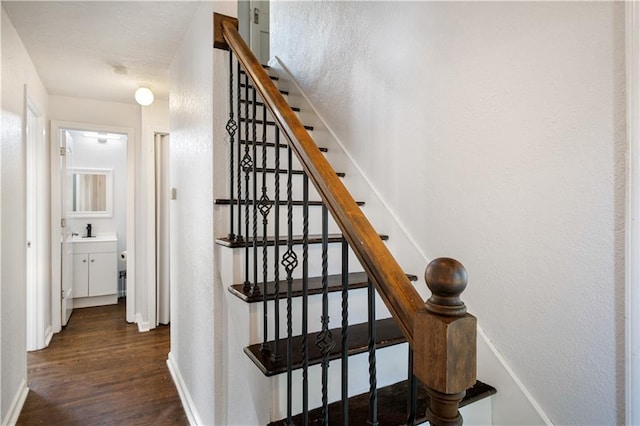 staircase with wood finished floors, baseboards, and a textured wall