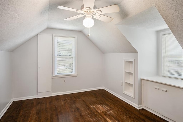 bonus room with built in shelves, a textured ceiling, baseboards, and hardwood / wood-style floors