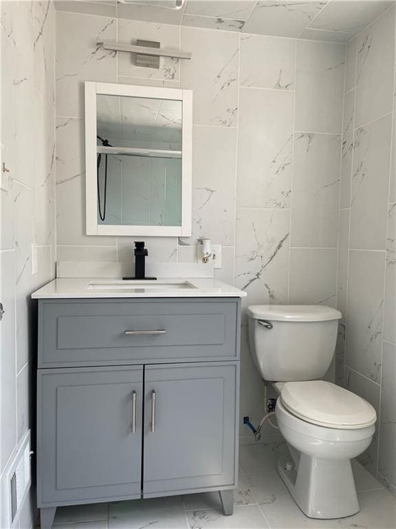 bathroom with visible vents, toilet, vanity, and marble finish floor