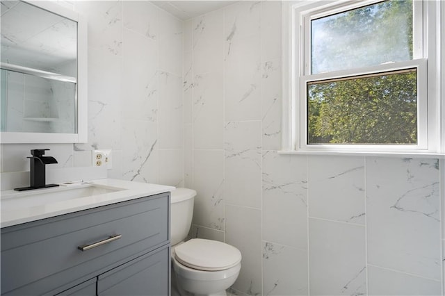 full bathroom featuring a shower, toilet, vanity, and tile walls