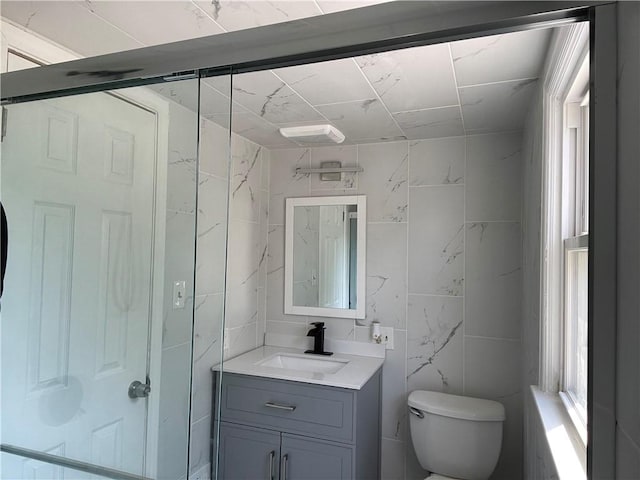 bathroom featuring vanity, tile walls, and toilet