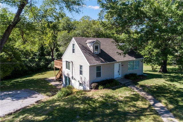 cape cod-style house with aphalt driveway, a deck, a front yard, and a shingled roof