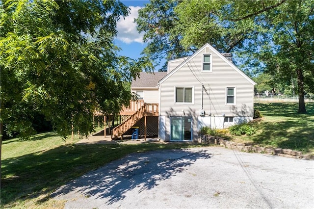 back of property featuring stairway, a lawn, and a deck