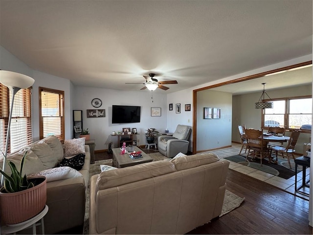 living area featuring baseboards, dark wood-type flooring, and ceiling fan