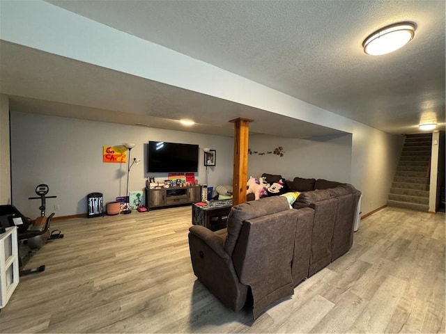 living room featuring stairway, baseboards, light wood-type flooring, and a textured ceiling