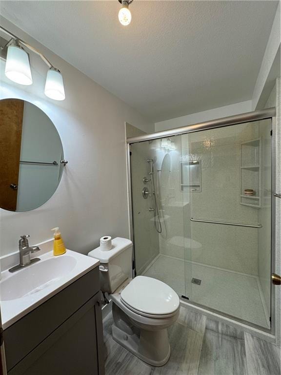 full bath with vanity, toilet, wood finished floors, and a shower stall