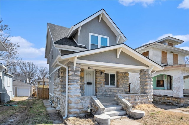 view of front of house with fence, a porch, stucco siding, an outdoor structure, and stone siding