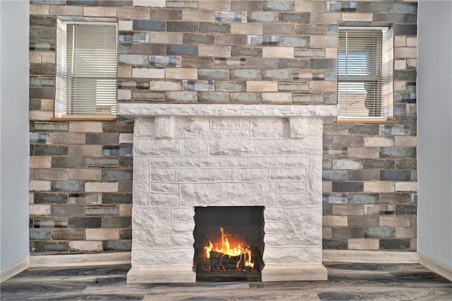 details with a stone fireplace, baseboards, and wood finished floors