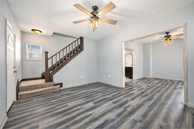 unfurnished living room featuring stairs, a ceiling fan, and baseboards