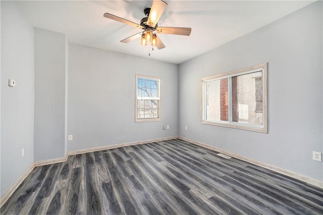 spare room with baseboards, dark wood-style flooring, and ceiling fan