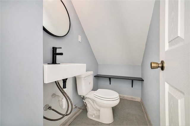 bathroom featuring a sink, toilet, baseboards, and vaulted ceiling