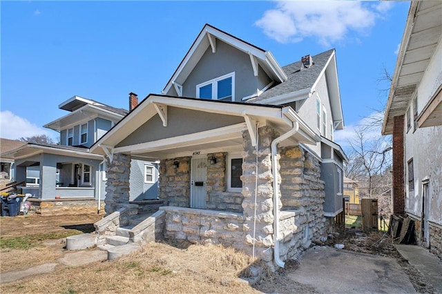 view of front of house with stucco siding, stone siding, and a porch