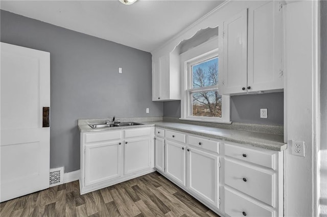 kitchen featuring visible vents, light countertops, dark wood-style floors, white cabinets, and a sink